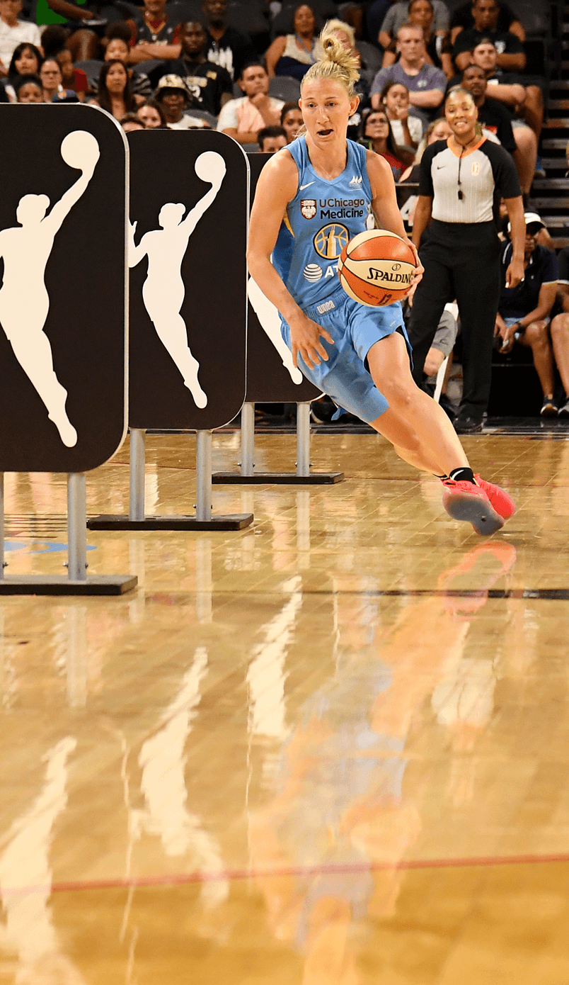 WNBA player in a light blue Chicago Sky uniform dribbles through WNBA logo obstacle panels during a skills challenge