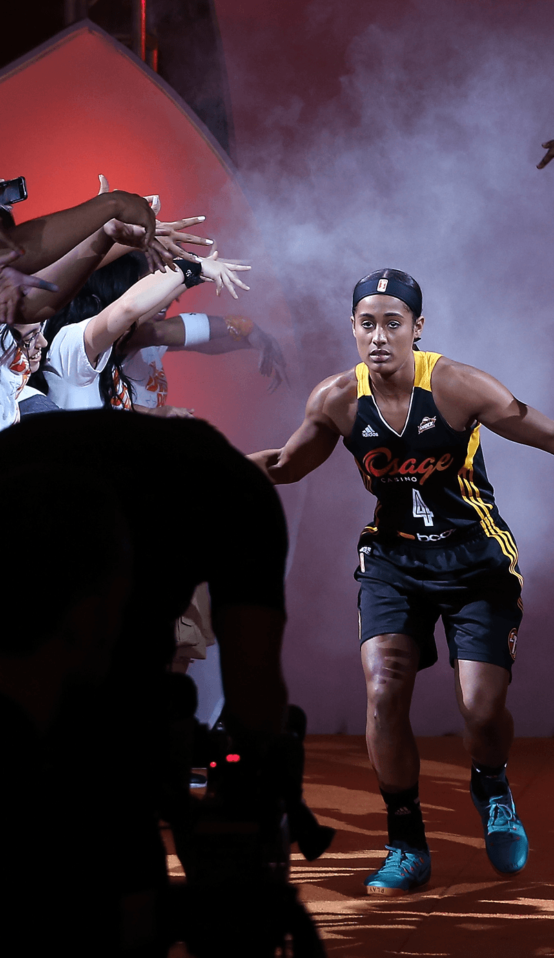 WNBA player runs onto the court through a smoke-filled tunnel, high-fiving fans reaching out from both sides